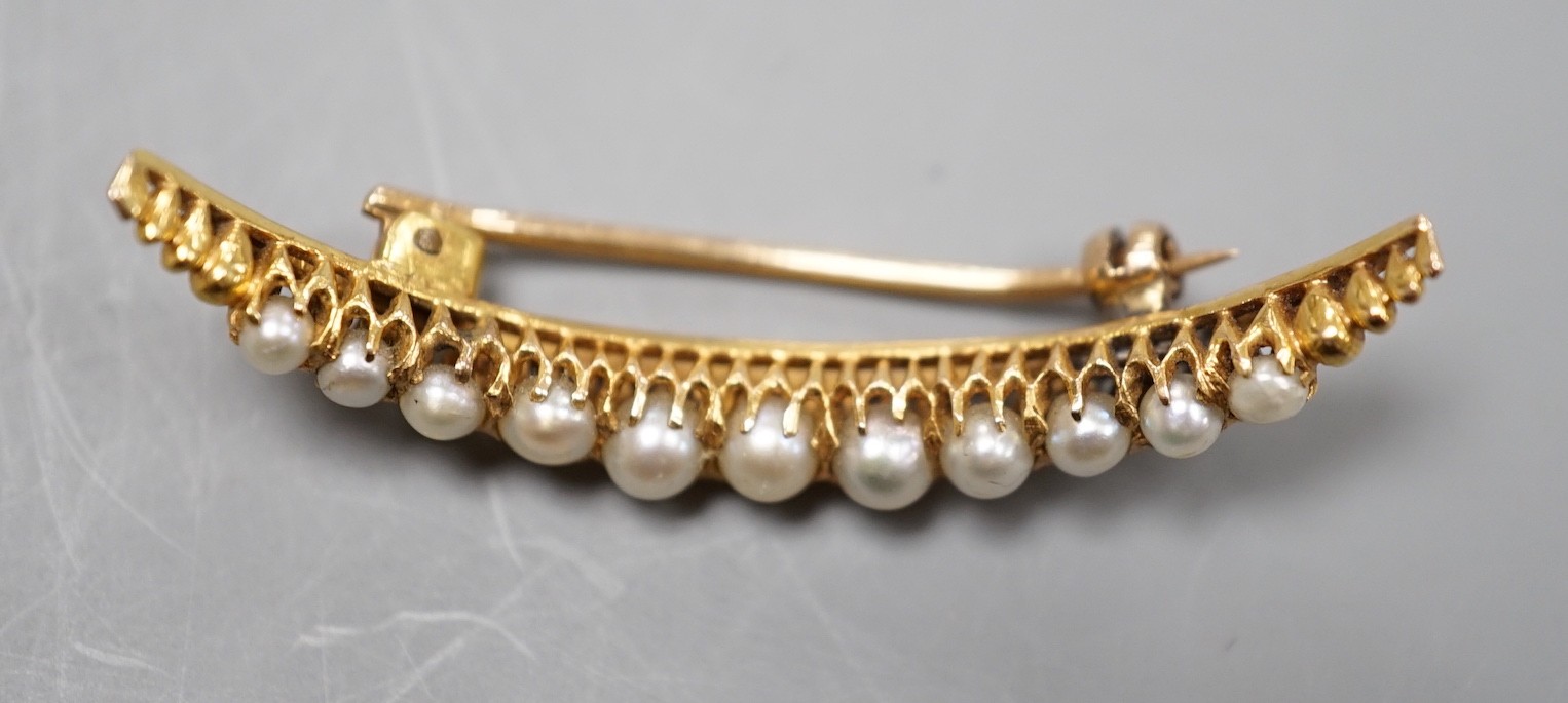 An early 20th century yellow metal and graduated cultured pearl set crescent brooch, 40mm, gross weight 3.7 grams.